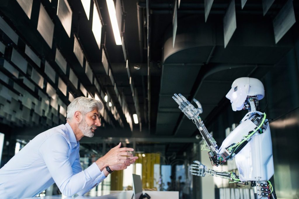 Imagem com uma pessoa e um robot com forma humana